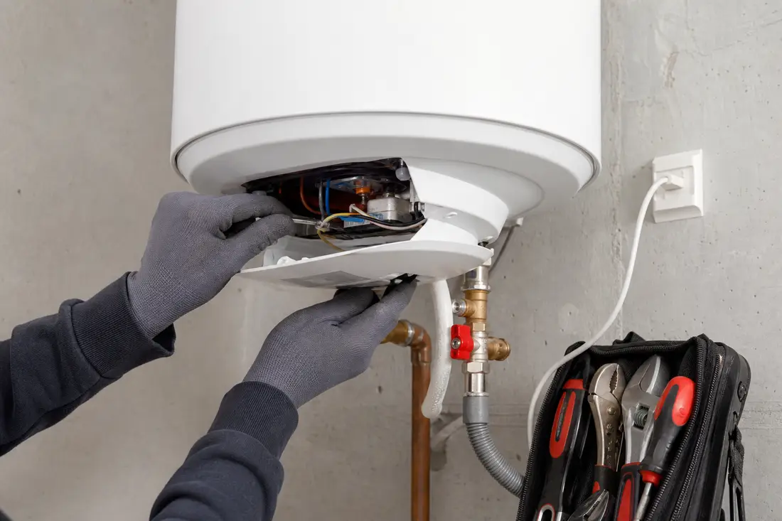 Mains gantées contrôlant un boiler électrique mural lors d'un entretien de chauffe-eau